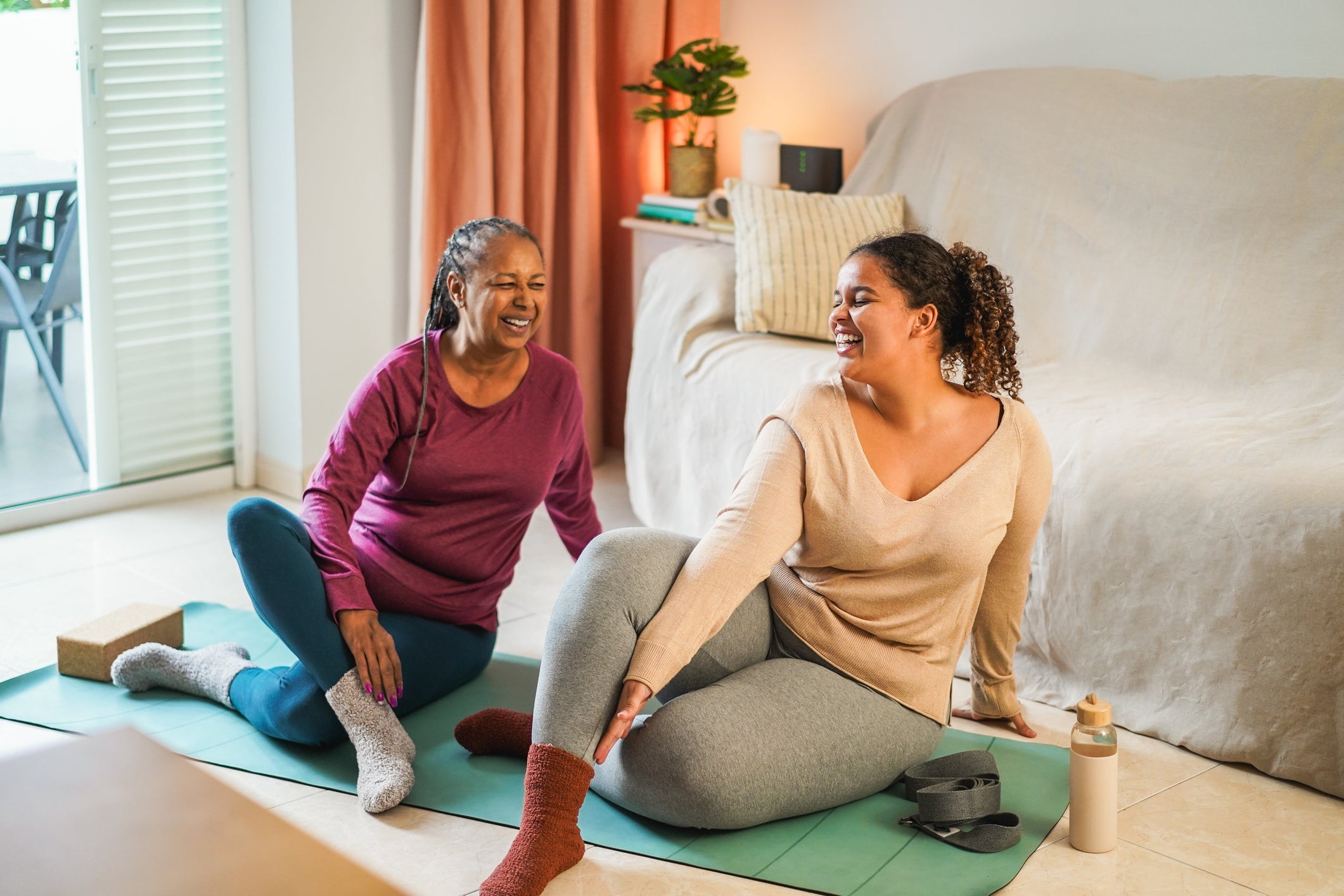2 women working out on yoga mat in an apartment