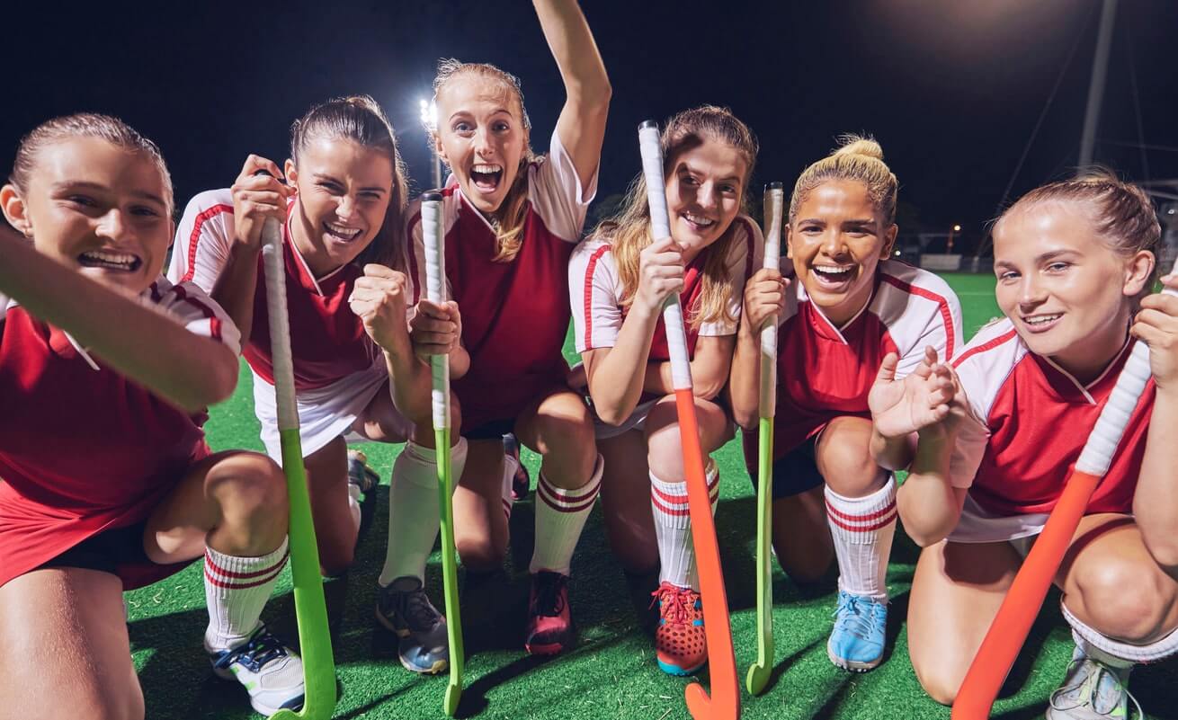 a group of smiling women's field hockey players