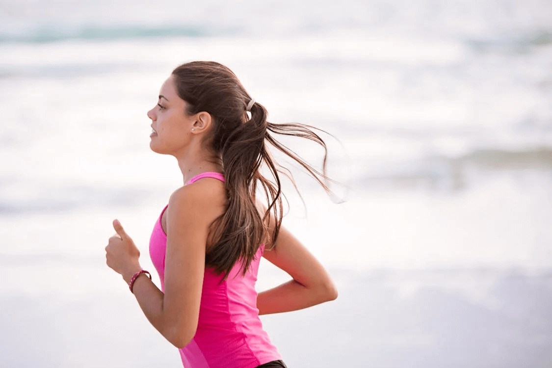 a woman running with the ocean behind her