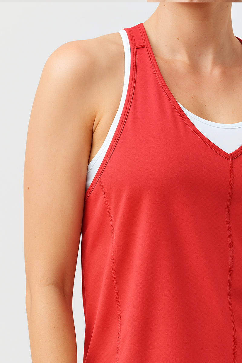 A person wears the Mesh It To Me Tank, a sleeveless red workout top layered over a white sports bra, visible from shoulders to waist against a light background. This sweat-wicking athletic tank ensures comfort for any activity.