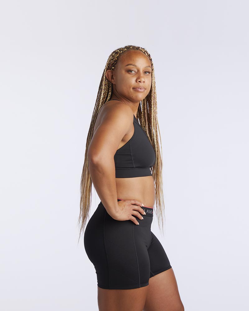 A woman wearing a 99er padded sports bra in black in a side angle.