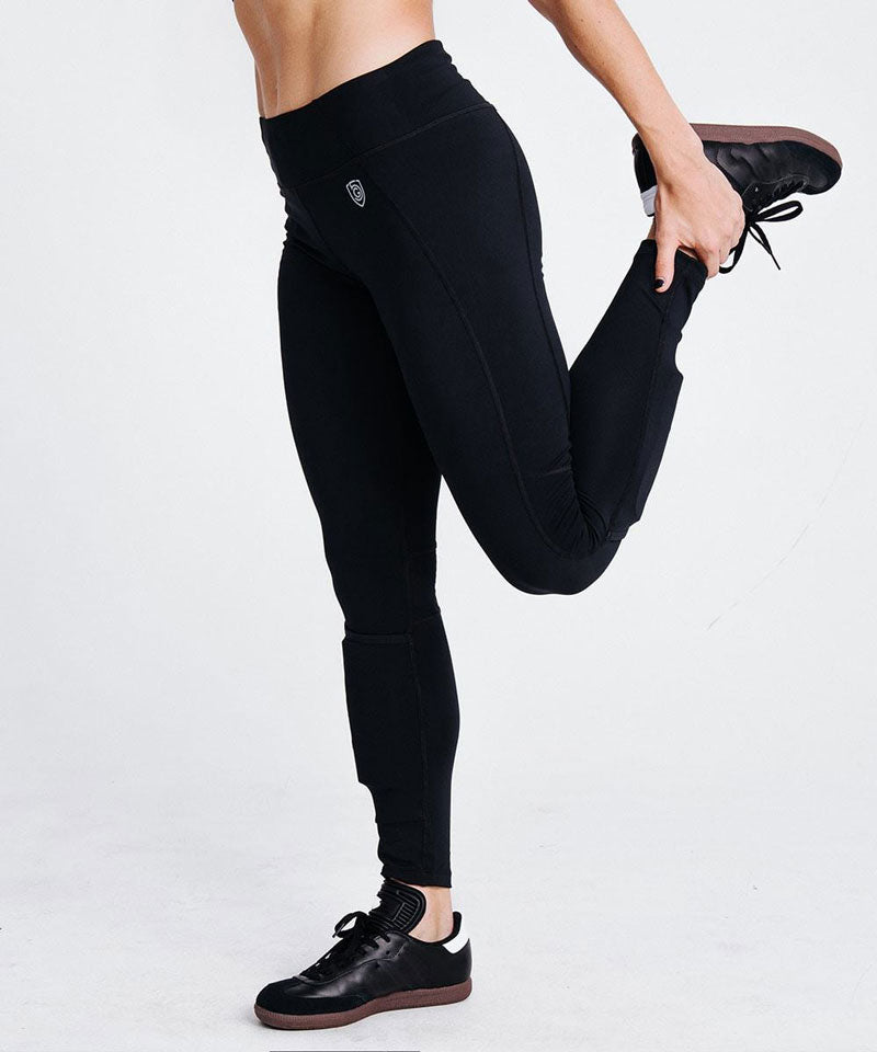 A woman stretches wearing the Combo Shin Guard Tight women's soccer pants.