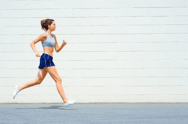 A woman running in shorts and a sports bra