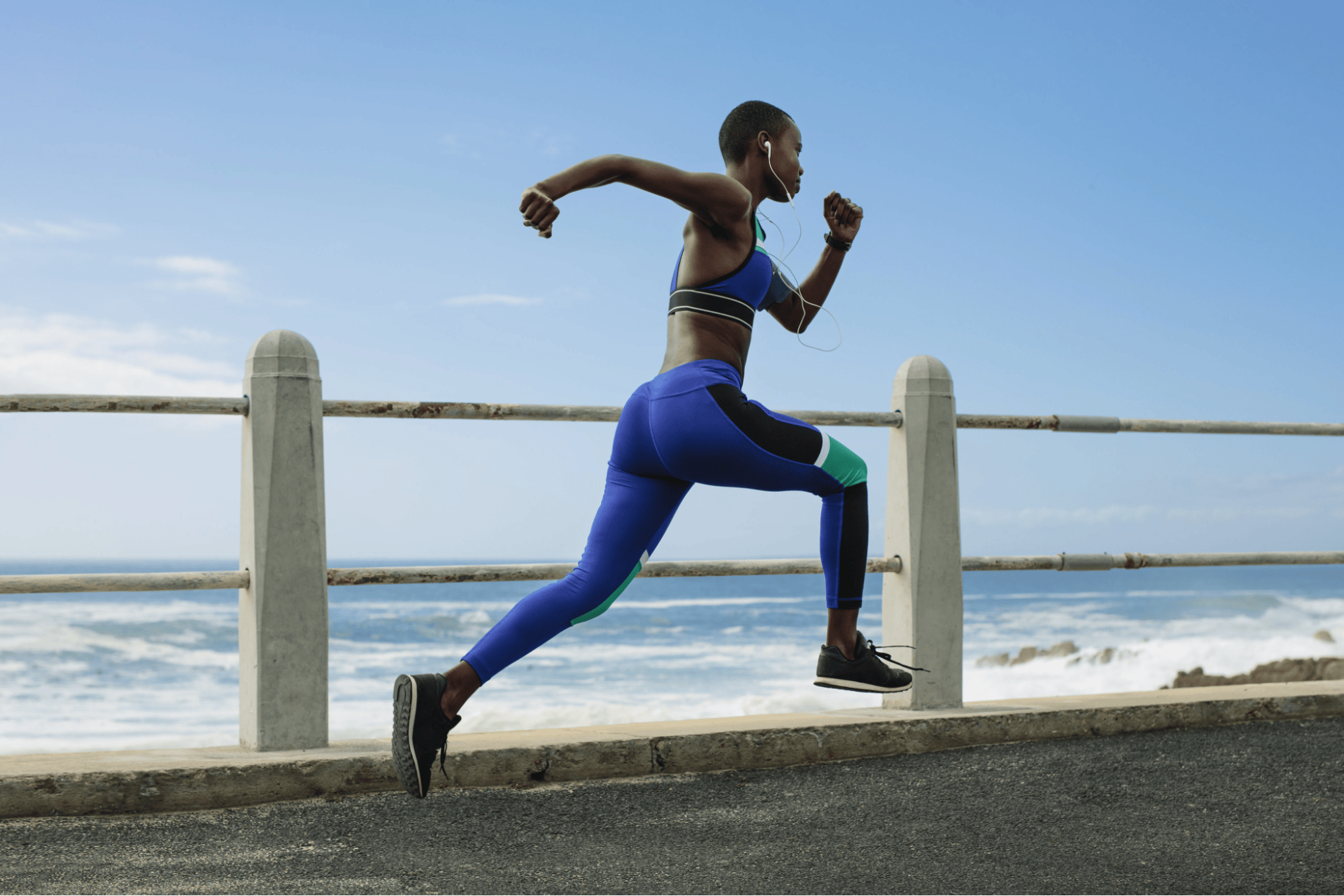 a woman running on a road near the ocean