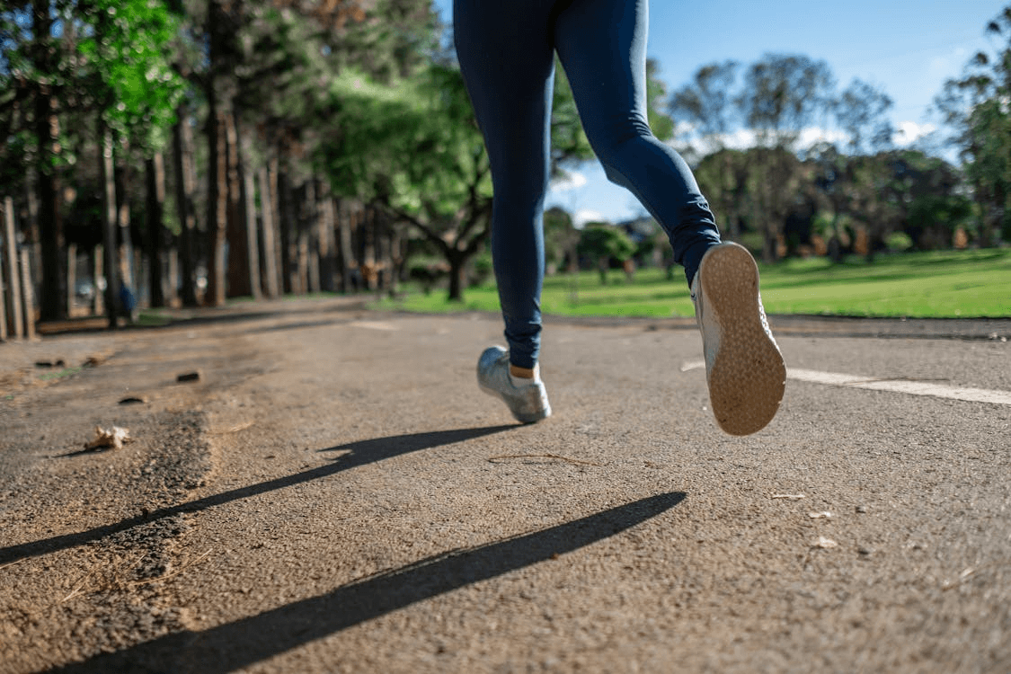 lower half of a woman wearing running leggings while running on a paved trail