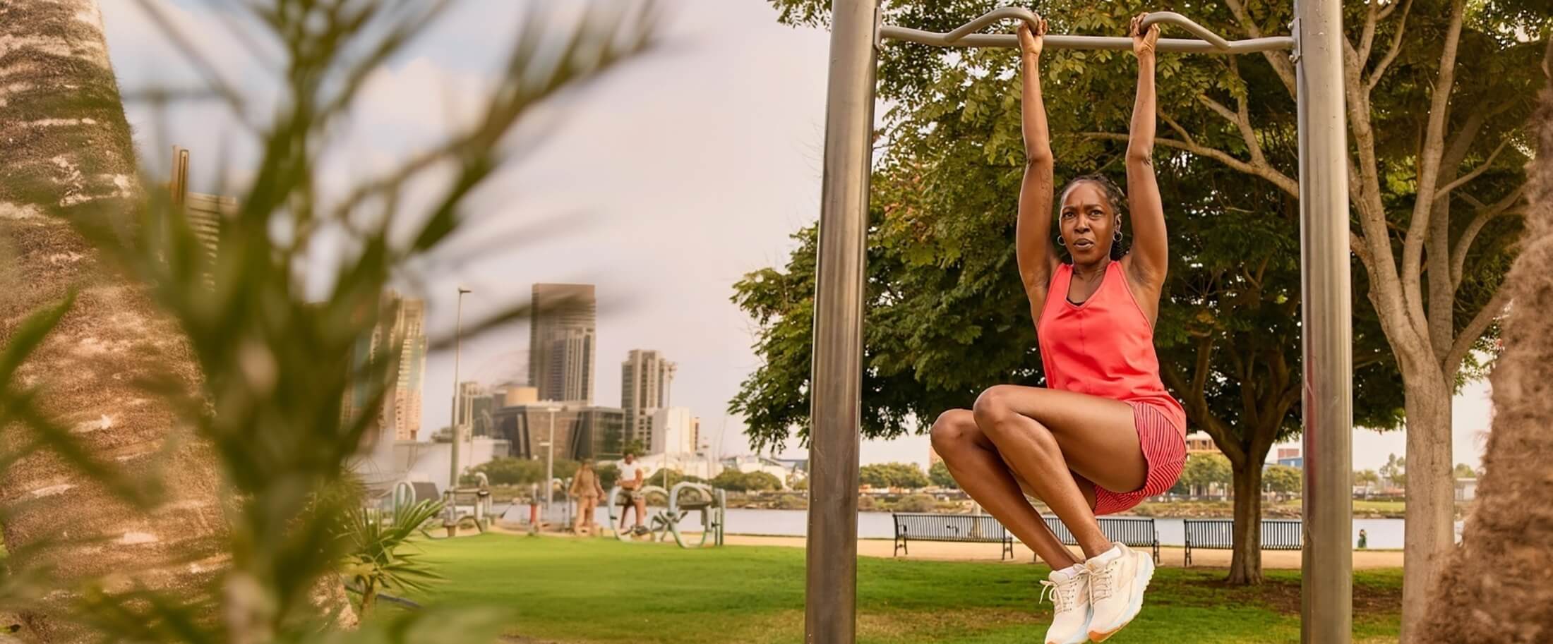 Four women walk together on a dirt path near the coast, with the ocean and cliffs in the background. They are dressed in athletic wear and appear to be enjoying a casual walk outdoors.