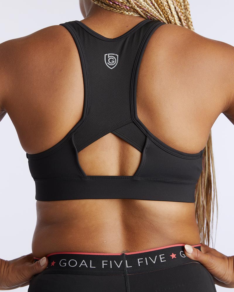 A women showing the back of a 99er padded sports bra in black.