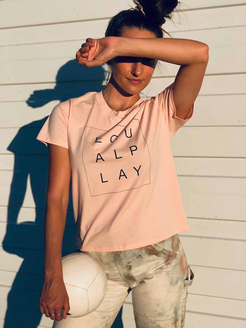 A model poses outside in natural light wearing the limited edition Equal Play ladies' box tee.