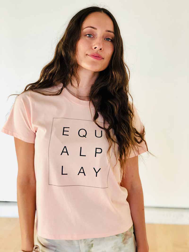 A model shows the relaxed fit of the 100% cotton Equal Play ladies' box tee.