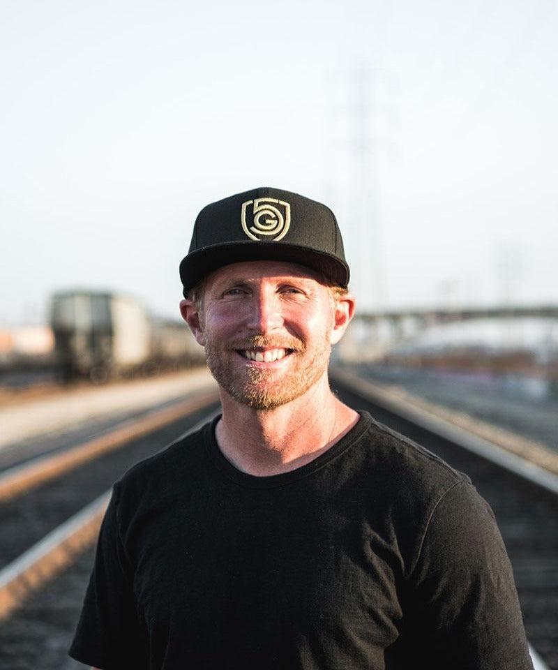 A man wears the Goal Five flat brim snap back hat.