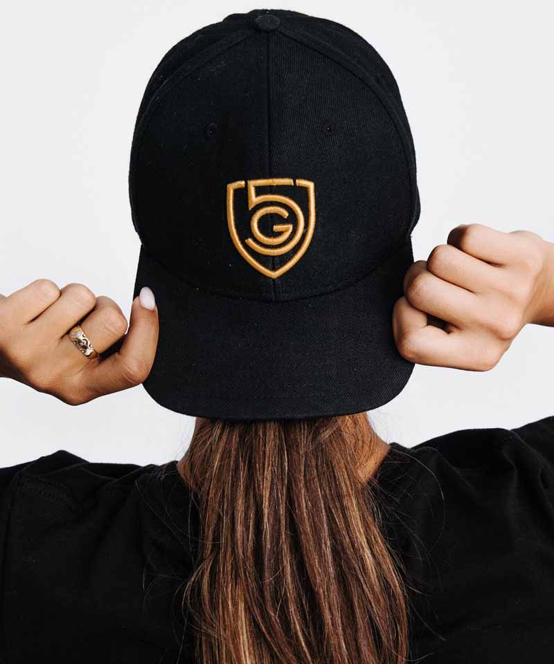 A woman wears the Goal Five snap back hat backwards.