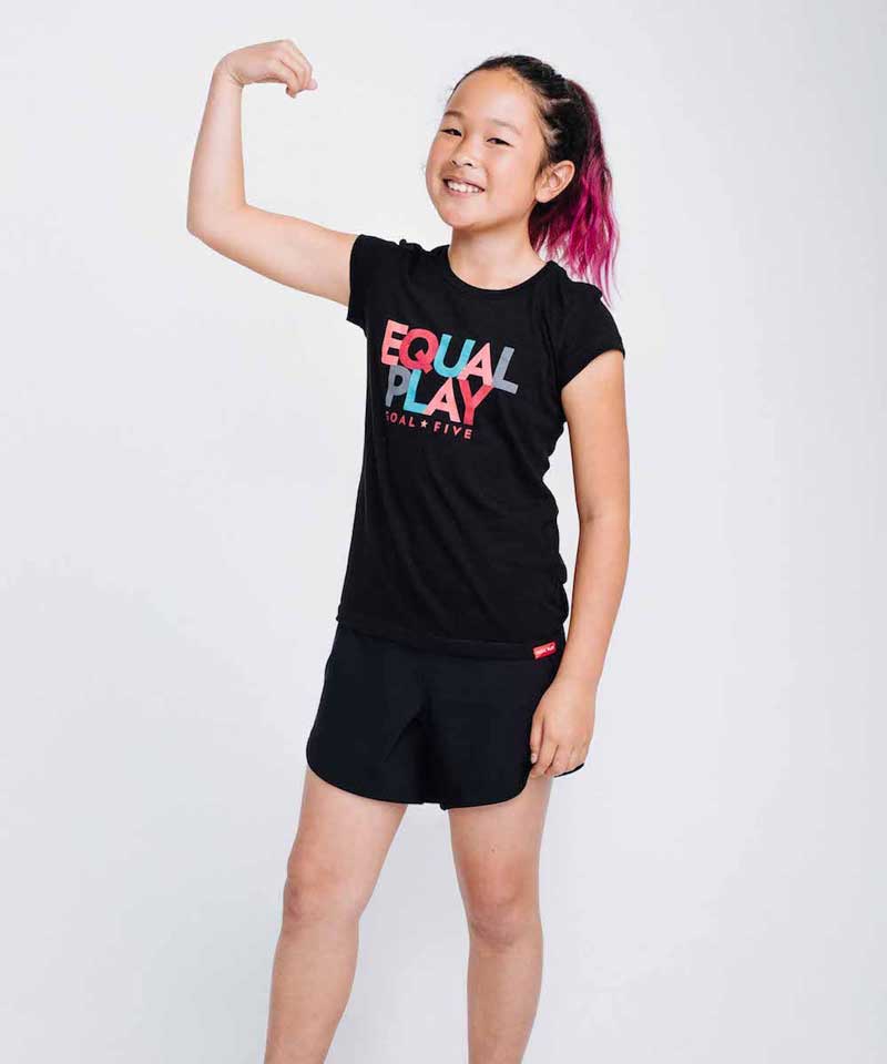 A young girl poses in the Equal Play girls' black T shirt.