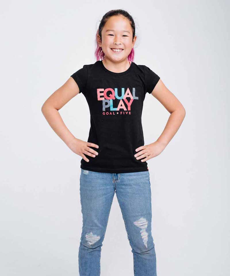 The model smiles wearing the Equal Play girls' black T shirt.