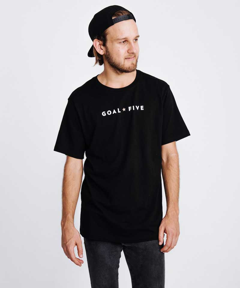 A man wears the Goal Five black cotton men's T shirt.