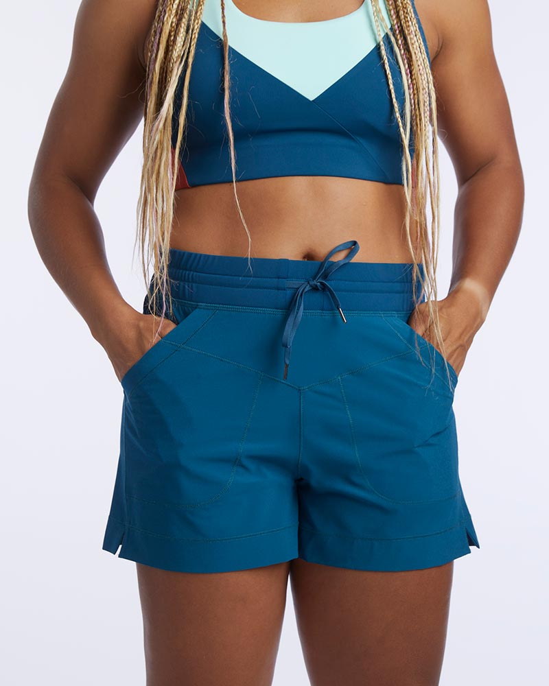 A woman uses the front hand pockets of Triple V women's athletic shorts with pockets.